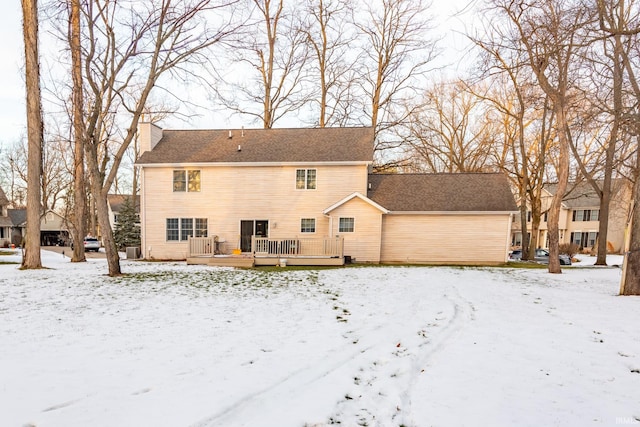 snow covered rear of property with a wooden deck