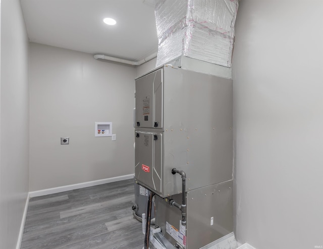 clothes washing area featuring hardwood / wood-style flooring, hookup for an electric dryer, hookup for a washing machine, and heating unit