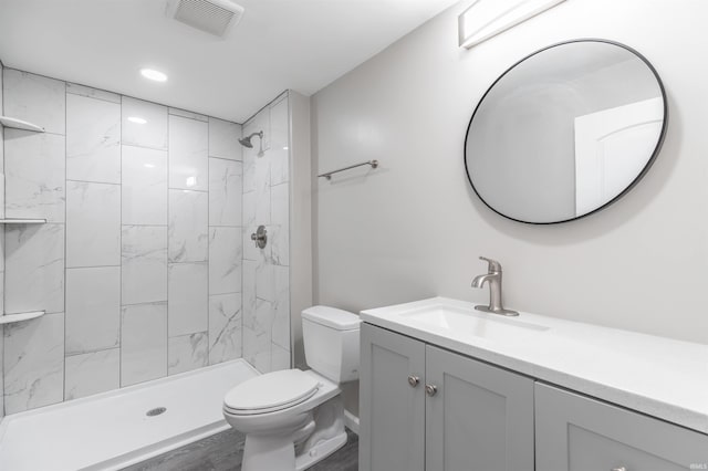 bathroom featuring vanity, toilet, hardwood / wood-style floors, and a tile shower