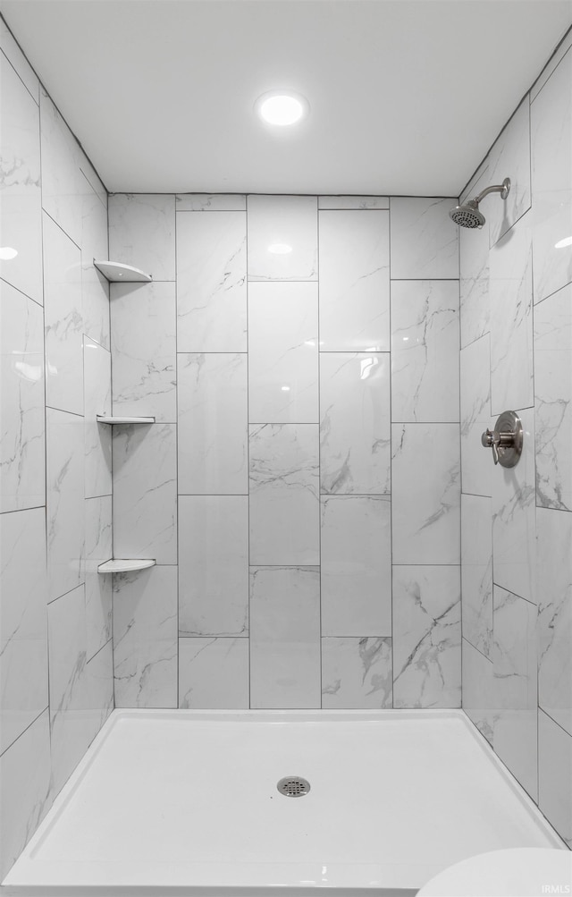 bathroom with toilet and a tile shower