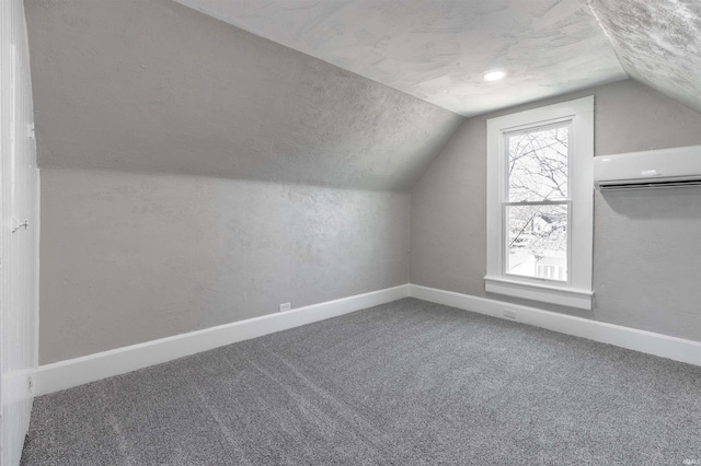 bonus room with lofted ceiling, carpet flooring, a wall unit AC, and a textured ceiling