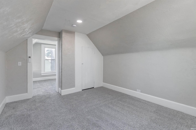 additional living space with lofted ceiling, a textured ceiling, and carpet