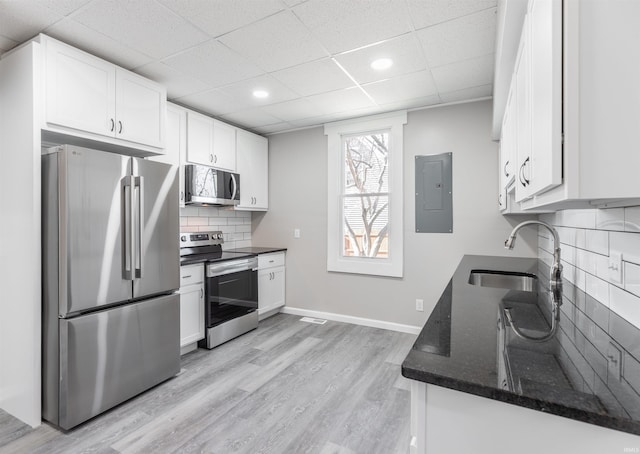 kitchen featuring sink, tasteful backsplash, appliances with stainless steel finishes, dark stone counters, and white cabinets