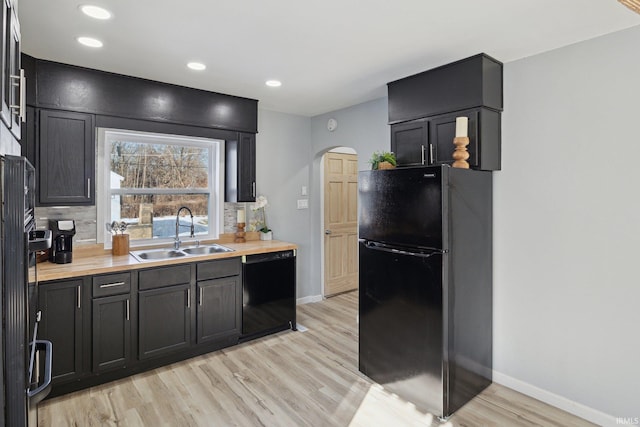 kitchen with sink, light hardwood / wood-style flooring, butcher block countertops, and black appliances