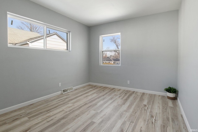 spare room with plenty of natural light and light hardwood / wood-style flooring