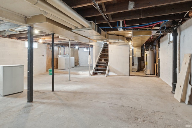 basement with stainless steel refrigerator, heating unit, washer and dryer, and gas water heater