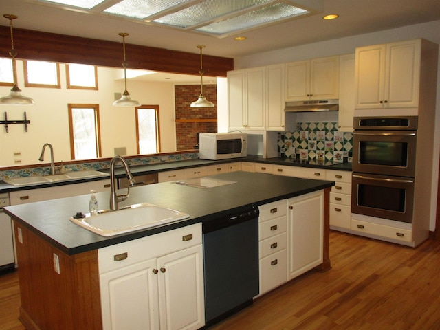 kitchen featuring appliances with stainless steel finishes, a kitchen island with sink, sink, and hanging light fixtures