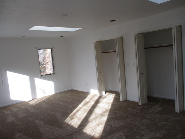 unfurnished bedroom featuring dark carpet and two closets