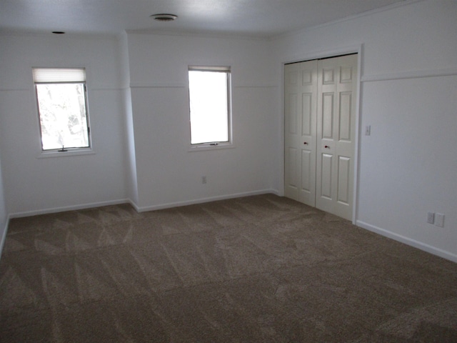 unfurnished room featuring dark colored carpet and a wealth of natural light