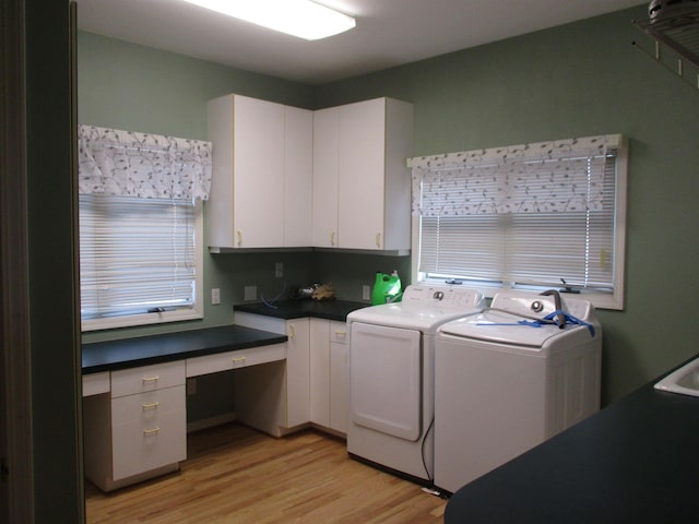 clothes washing area featuring washing machine and dryer, cabinets, and light wood-type flooring