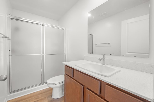 bathroom featuring vanity, a shower with shower door, toilet, and wood-type flooring