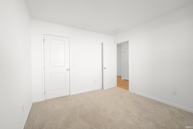 unfurnished bedroom with light colored carpet and a closet