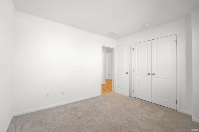 unfurnished bedroom featuring light carpet and a closet