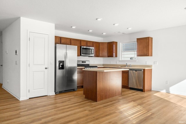 kitchen with a kitchen island, appliances with stainless steel finishes, sink, and light hardwood / wood-style flooring