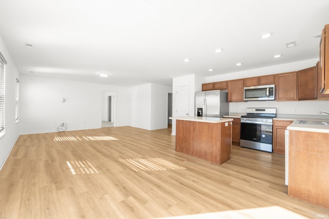 kitchen with sink, stainless steel appliances, a center island, and light wood-type flooring