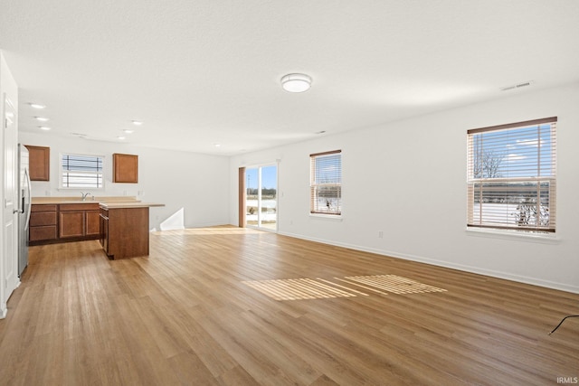 unfurnished living room featuring sink and light wood-type flooring