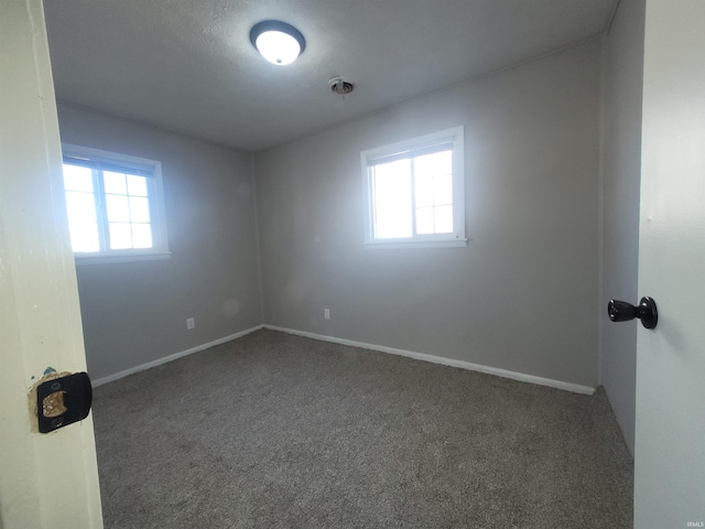 empty room with dark carpet and a healthy amount of sunlight