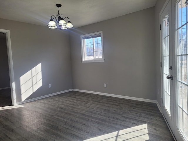 empty room with an inviting chandelier and dark hardwood / wood-style flooring