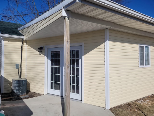 view of exterior entry with central AC unit and a patio