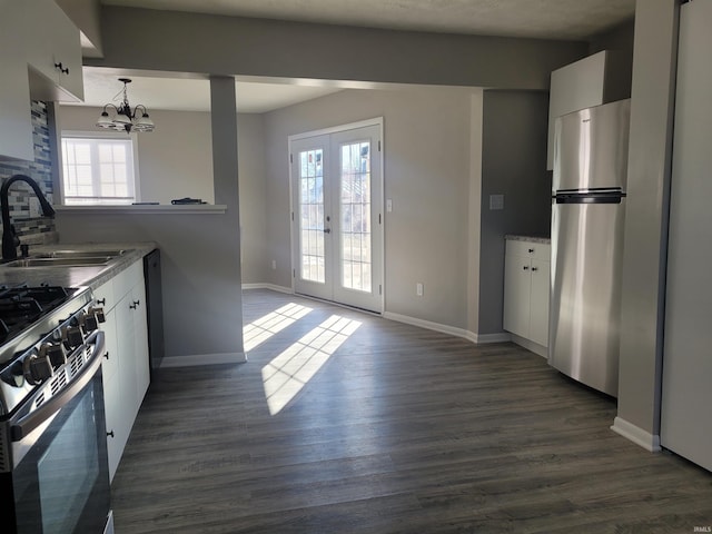 kitchen featuring sink, stainless steel refrigerator, hanging light fixtures, plenty of natural light, and white cabinets