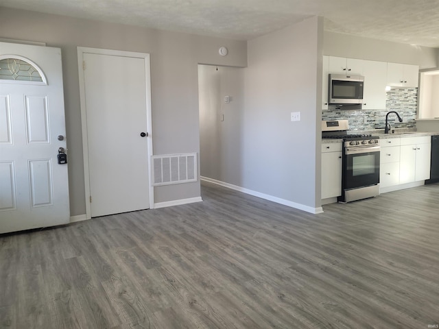 kitchen with sink, white cabinets, decorative backsplash, stainless steel appliances, and dark wood-type flooring