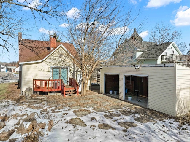 snow covered property with a garage and a deck