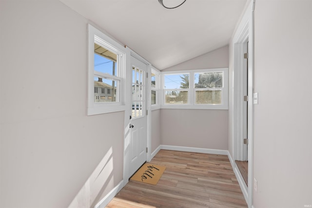 doorway to outside with vaulted ceiling and light wood-type flooring