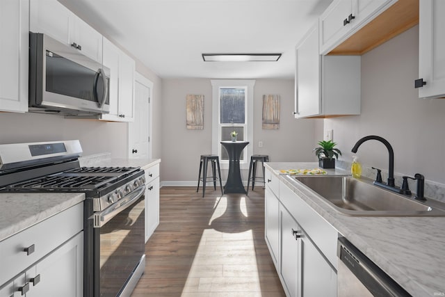 kitchen featuring white cabinetry, appliances with stainless steel finishes, dark hardwood / wood-style flooring, and sink