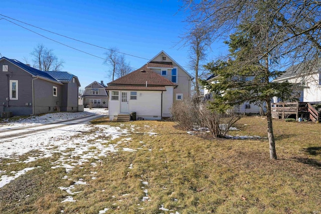 snow covered rear of property with a yard