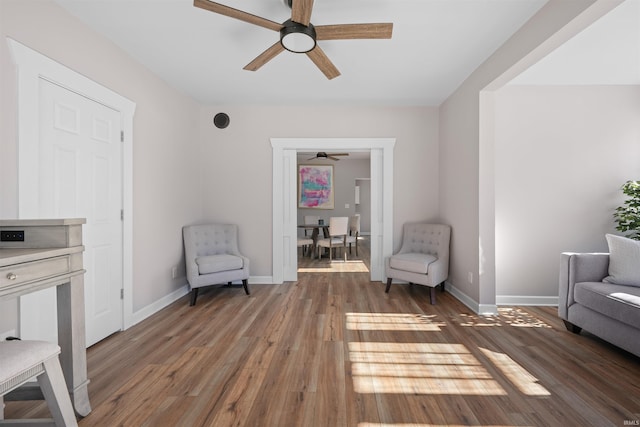 living area with ceiling fan and dark hardwood / wood-style flooring