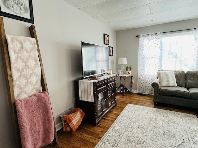 living room featuring a drop ceiling and dark hardwood / wood-style flooring