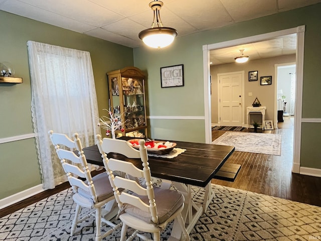 dining room with dark wood-type flooring and a paneled ceiling