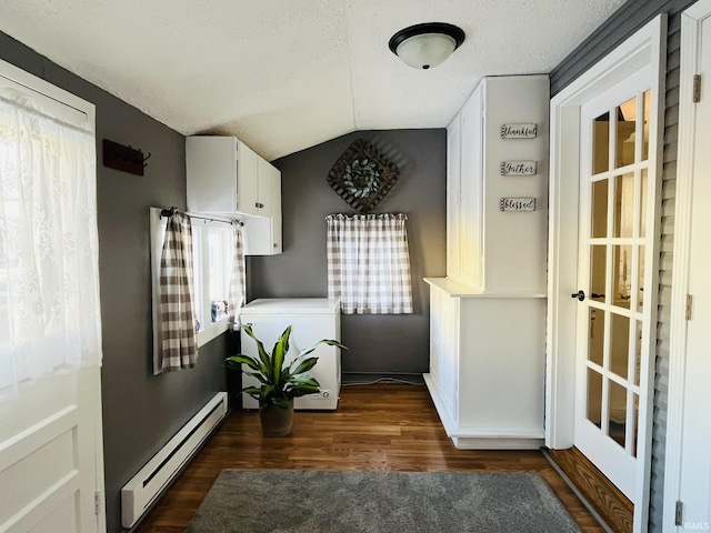 doorway to outside featuring a baseboard heating unit, a textured ceiling, dark hardwood / wood-style flooring, washer / clothes dryer, and vaulted ceiling