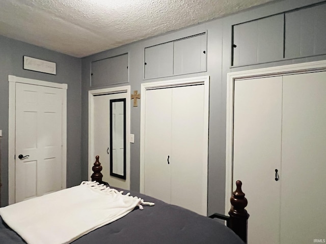 bedroom with multiple closets and a textured ceiling