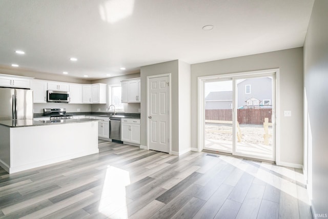 kitchen featuring white cabinetry, appliances with stainless steel finishes, a healthy amount of sunlight, and light hardwood / wood-style flooring