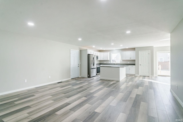 kitchen featuring white cabinets, a center island, stainless steel fridge, and light hardwood / wood-style floors