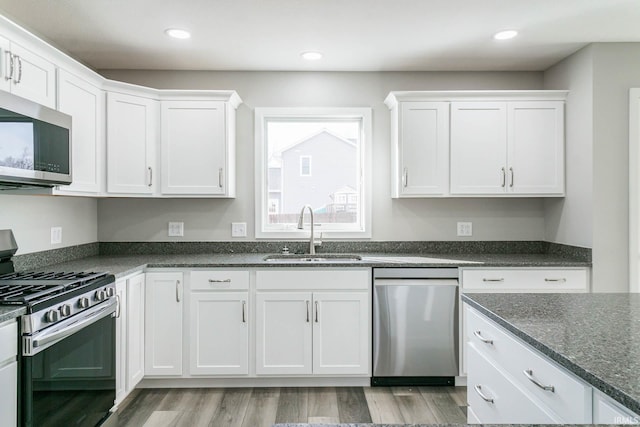 kitchen with sink, light hardwood / wood-style flooring, white cabinets, and appliances with stainless steel finishes