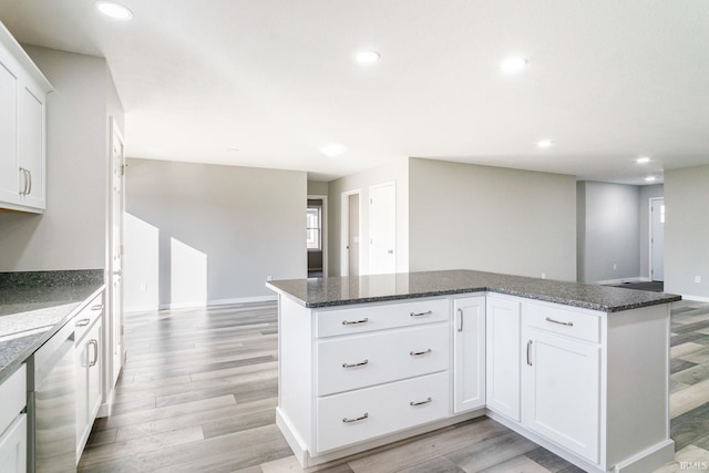 kitchen featuring white cabinetry, stainless steel dishwasher, dark stone counters, and light hardwood / wood-style flooring