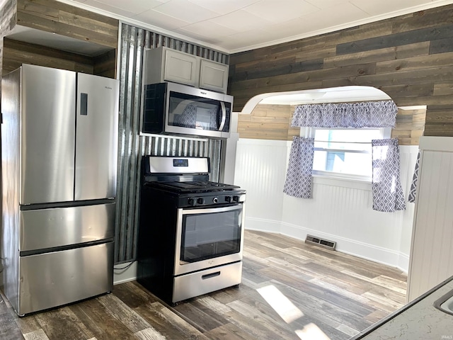 kitchen featuring wood walls, gray cabinetry, dark hardwood / wood-style floors, stainless steel appliances, and light stone countertops