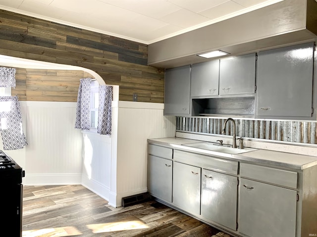 kitchen featuring sink, crown molding, wooden walls, and hardwood / wood-style floors