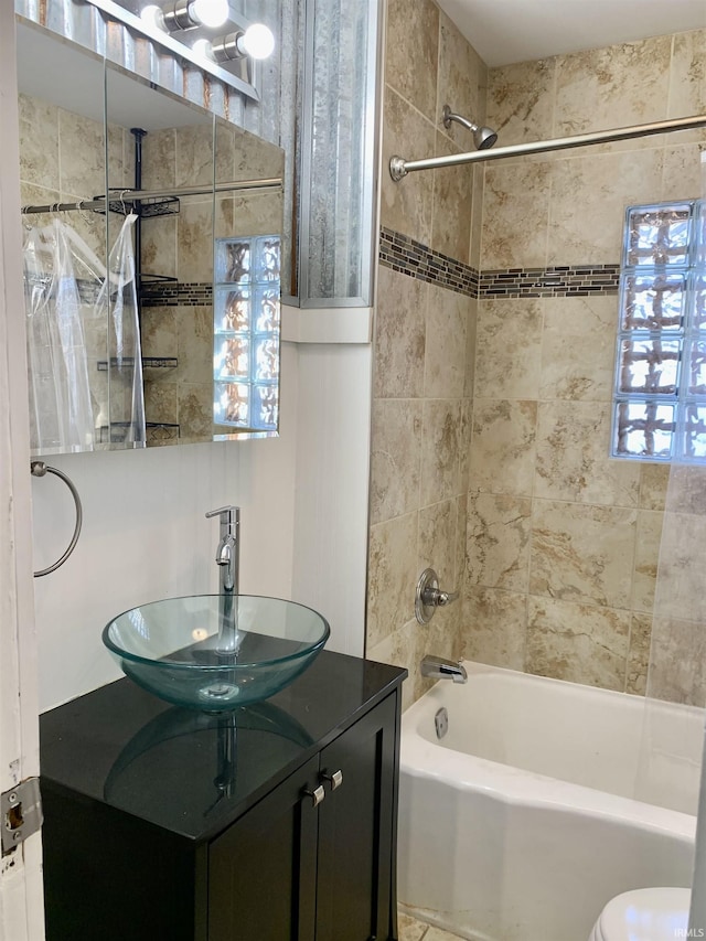 full bathroom featuring tiled shower / bath, vanity, and toilet