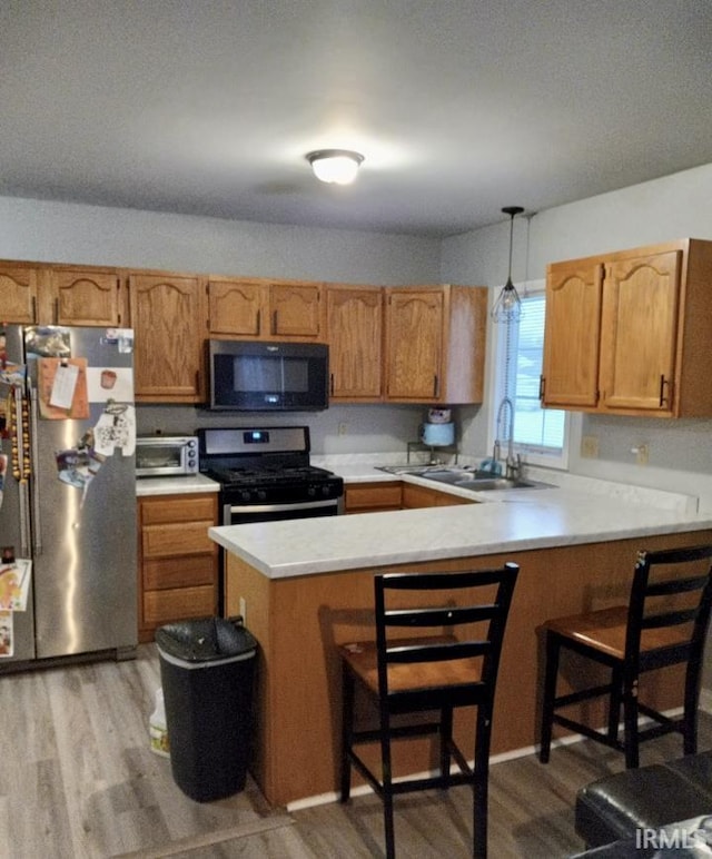 kitchen featuring a breakfast bar, sink, decorative light fixtures, kitchen peninsula, and stainless steel appliances