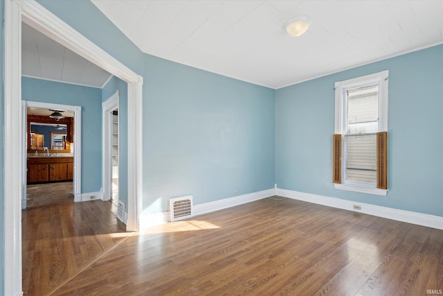 empty room with crown molding, dark hardwood / wood-style floors, and sink