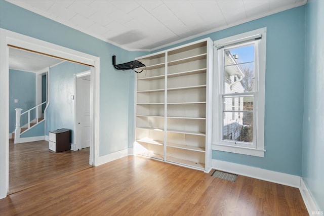 empty room with hardwood / wood-style floors, ornamental molding, and a healthy amount of sunlight