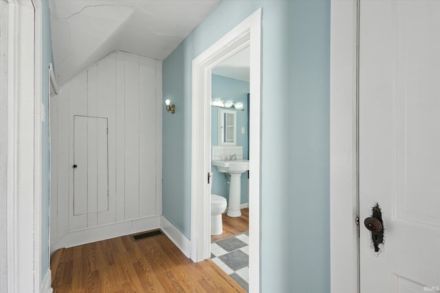 hall with vaulted ceiling and light hardwood / wood-style flooring