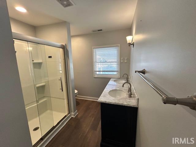 bathroom featuring vanity, wood-type flooring, toilet, and a shower with shower door