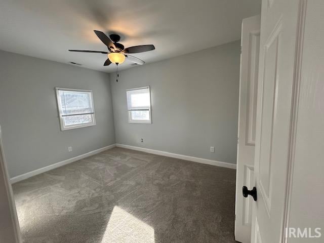 spare room with ceiling fan and dark colored carpet