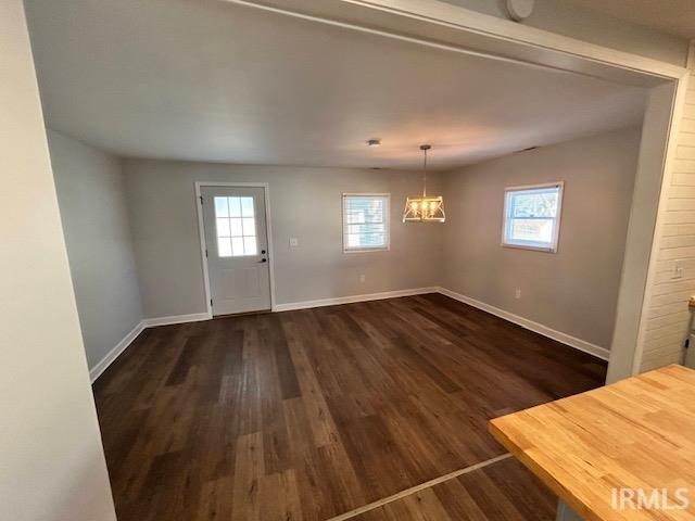 interior space featuring dark wood-type flooring, a healthy amount of sunlight, and a chandelier