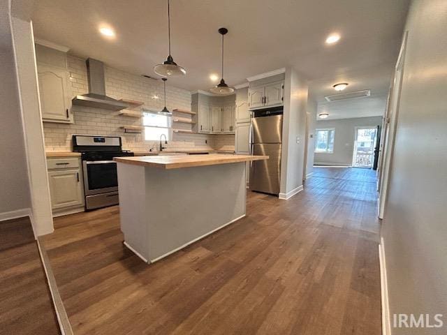 kitchen featuring wall chimney exhaust hood, a center island, hanging light fixtures, stainless steel appliances, and decorative backsplash