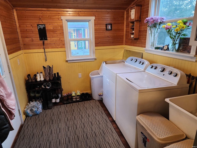 washroom with separate washer and dryer, sink, and wooden walls